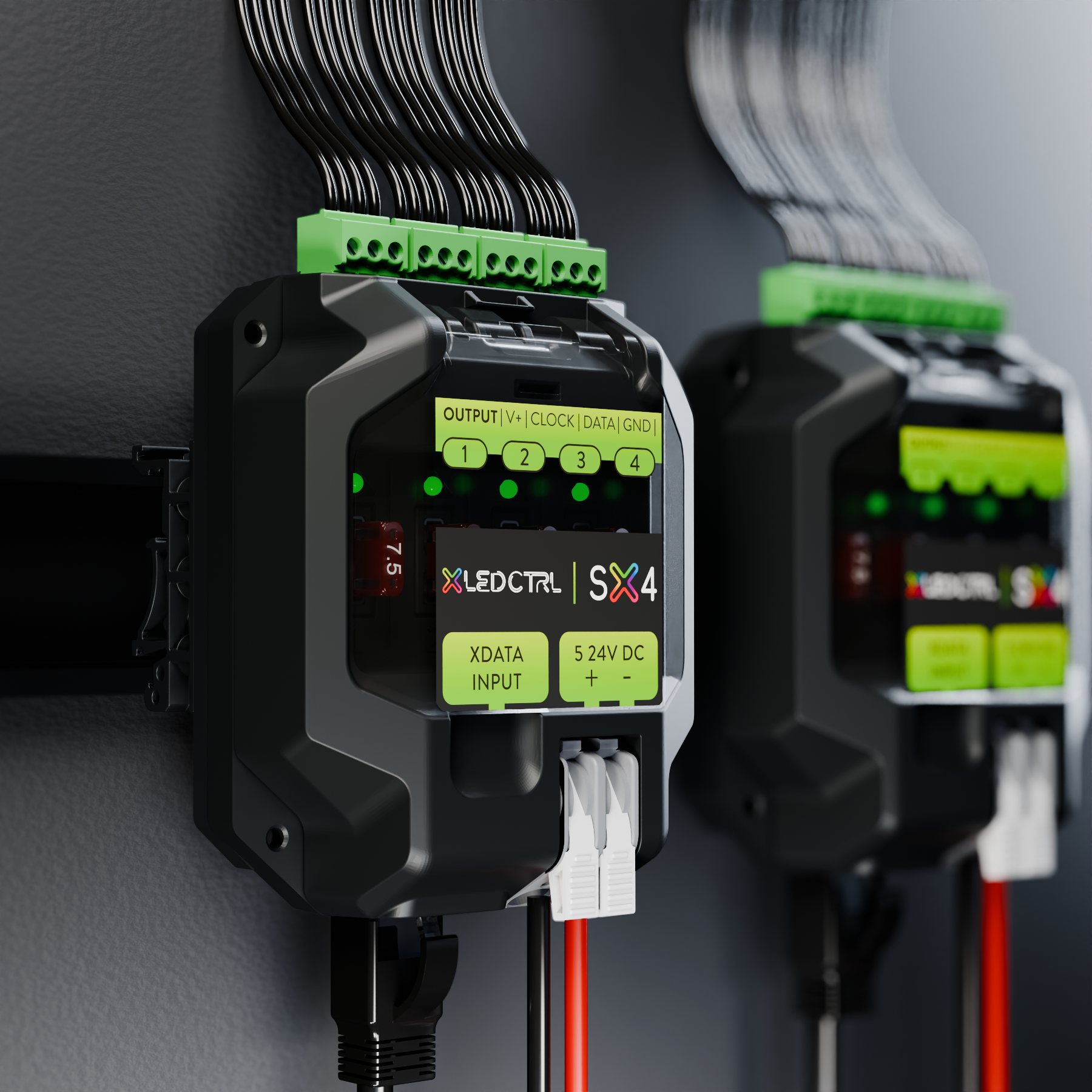 Two SX4 Long Range Receivers mounted side by side on DIN rail inside an equipment cabinet, the four numbered pixel outputs and their indicator LEDs across the front, terminal blocks wired along the top edge and the data input and quick-connect power clamps below